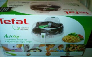 A box of Tefal ActiFry, an air fryer, shows the product image, the Tefal logo, and text stating “1 spoonful of oil for 1 kg of real crispy chips!” Various meal pictures and instructions are visible on the lower part of the packaging.