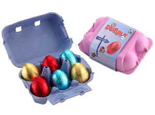 A purple egg box, open to reveal six shiny, foil-wrapped chocolate eggs in gold, red, and blue. Next to it is a closed pink box with a label featuring a red egg and playful graphics.