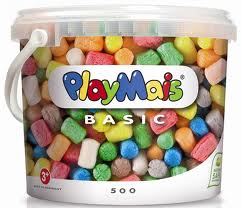 A plastic tub labelled "PlayMais BASIC" contains colourful, cylindrical foam building pieces. The tub has a white handle and lid, and the packaging displays the PlayMais logo in playful, multicoloured letters. The set is for ages 3 and up.
