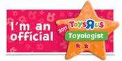 A rectangular badge with a pink background reads, "I'm an official" on the left. On the right, an orange star features the 2011 Toys"R"Us logo above a green ribbon labelled "Toyologist" with two pink stars below it.