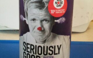 A jar of "Seriously Good Butter Chicken Indian Sauce by Gordon Ramsay." The label shows a black-and-white photo of Gordon Ramsay with a red clown nose. A red circle says, "10p to Comic Relief from every jar" and notes this is for Red Nose Day.