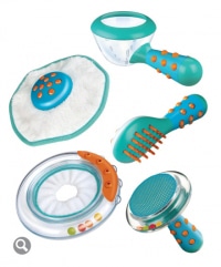 A set of five colourful plastic pet grooming tools in turquoise, white, and orange, including a brush, a round rubber massager, a shedding tool, a round grooming mitt, and a ring-shaped toy with coloured beads inside.