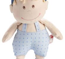 A soft plush doll with beige skin, yellow yarn hair, and a blue cap with green stripes. The doll wears blue dungarees with small polka dots, blue fabric shoes, and has stitched eyes, nose, and a smiling mouth. The doll's arms are outstretched.