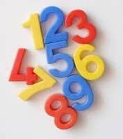 A group of colourful plastic numbers, 1 to 9, arranged in a scattered pile on a white background. The numbers are blue, red, and yellow, with each digit in a different colour, creating a playful and vibrant appearance.