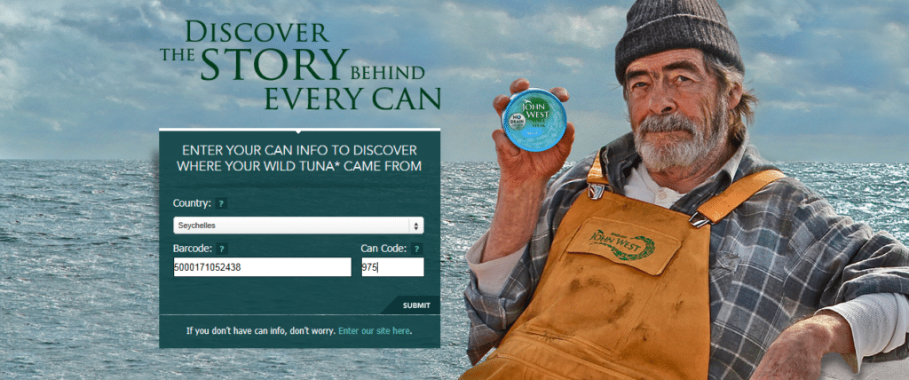 A bearded man in yellow overalls and a green shirt sits holding a tin of Ocean Mist tuna. Beside him is a form to enter a country and tin code to trace the origin of wild tuna, with “DISCOVER THE STORY BEHIND EVERY TIN” written above.