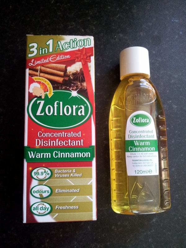 A bottle and box of Zoflora Concentrated Disinfectant in Warm Cinnamon scent. The box highlights features like "3 in 1 Action," "Limited Edition," "99.9% bacteria & viruses killed," and "odours eliminated." The bottle contains 120ml of yellow liquid.