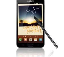 A Samsung smartphone with a stylus is displayed. The screen shows a sunset photo with silhouettes of people, white doodles resembling constellations, and the handwritten words "OUR HAPPY MOMENT." Four app icons are visible at the bottom of the screen.