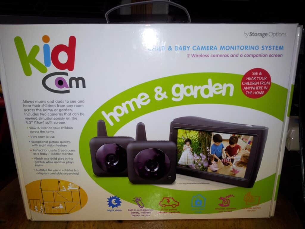 A product box for the “Kid Cam” Child & Baby Camera Monitoring System. The box shows two black cameras and a screen displaying children playing in a garden. Bright colours and icons highlight features like 2 wireless cameras and home & garden monitoring.
