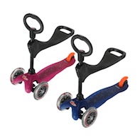 Two small three-wheeled scooters for children, one pink and one blue, each with a black seat, black handlebar, and orange accents on the rear. Both scooters have two front wheels and one rear wheel.