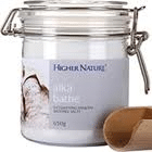 A clear jar labelled "Higher Nature" with white bath salts and a metal clasp lid is shown. The label reads “Magi Bath,” and there is a wooden scoop beside the jar. The background is white, and the product appears clean and spa-like.