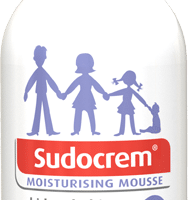 A white pump bottle labelled “Sudocrem Moisturising Mousse” with a purple cap. The label shows silhouettes of two adults and a child holding hands. Text highlights features for kids and babies, including “hypoallergenic” and “ProDerm Technology”.