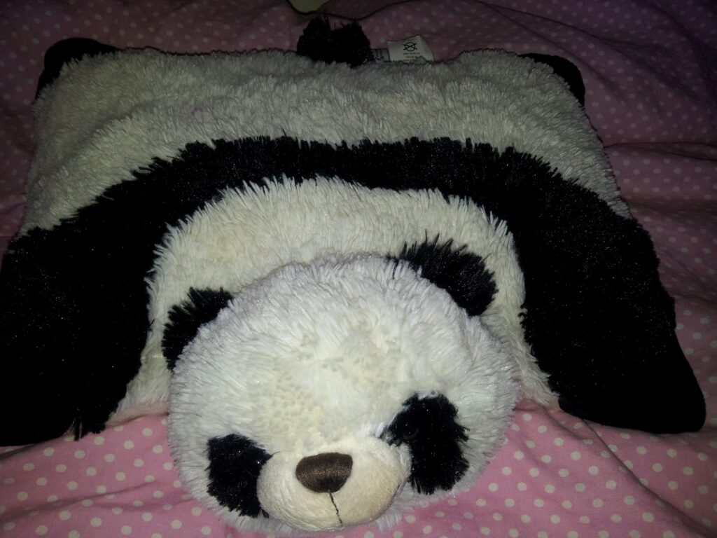 A stuffed panda bear on a pink polka dot blanket.
