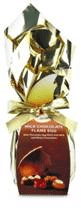 A chocolate Easter egg wrapped in shiny gold foil with a gold ribbon tied round it. The label features an image of assorted chocolates and text describing the product. The packaging looks festive and luxurious.