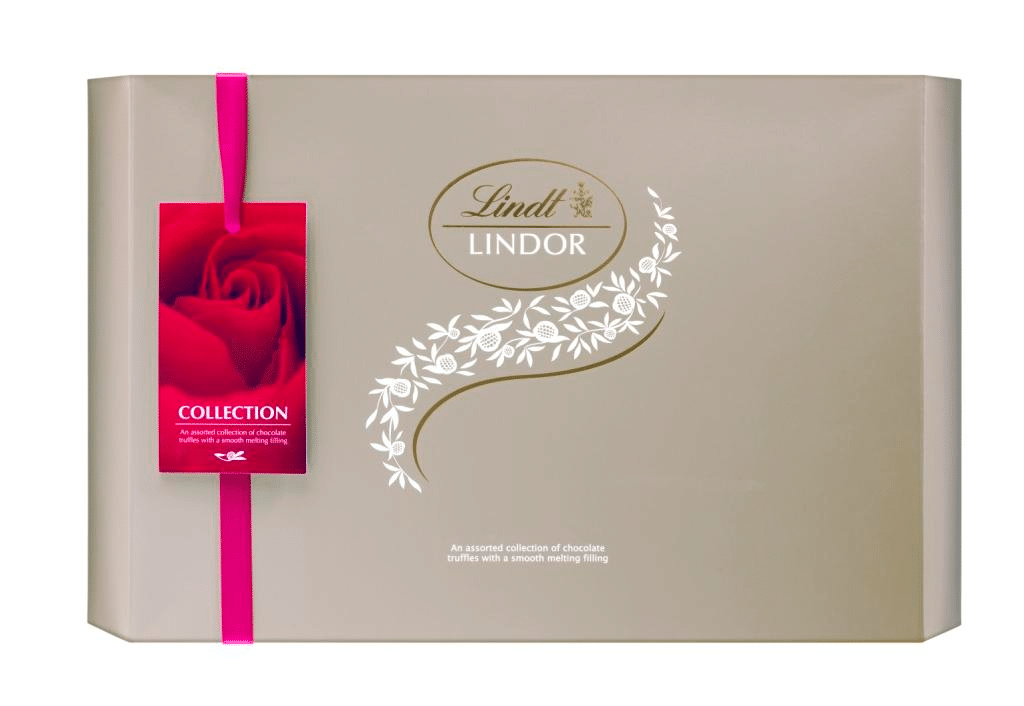 A large beige Lindt Lindor chocolate box with a pink ribbon and a red tag featuring a rose. The box has a white floral design and gold logo, and text reads "Collection: An assortment of chocolate truffles with a smooth melting filling.