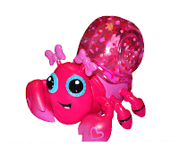 A bright pink toy crab with large blue eyes, a smiling face, and heart details on its claws. Its shell is transparent pink with glitter and star shapes inside, and two pink bows sit on its head. The crab has a playful, cartoon-like appearance.