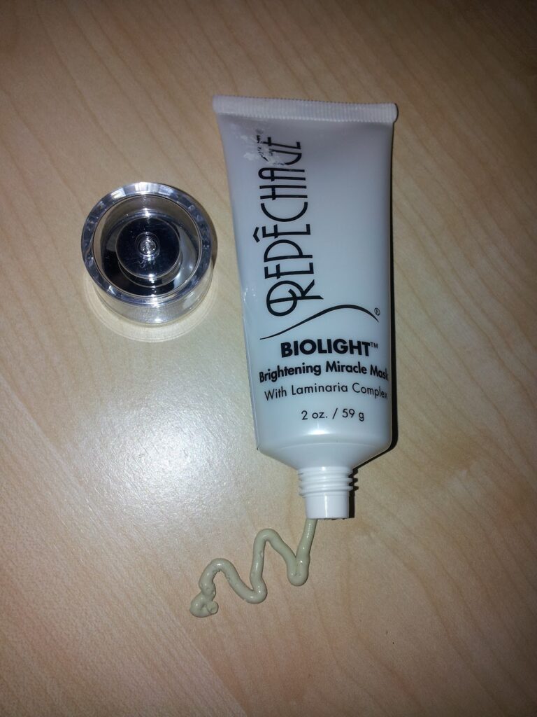 A white tube of face cream with a tube of liquid coming out of it.