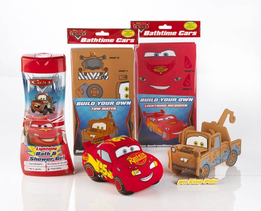 A Cars-themed bath set includes a red bath and shower gel bottle with Lightning McQueen, two “Build Your Own” bathtime foam car kits (Lightning McQueen and Tow Mater), and assembled foam models of both characters displayed in front.