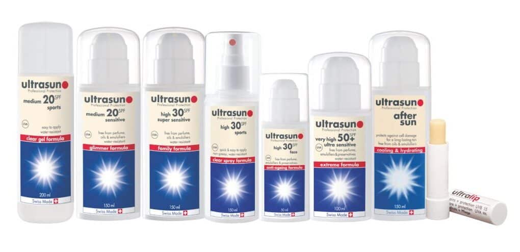 A row of nine Ultrasun suncream and skincare products, mostly in white bottles with blue labels. Each bottle shows the SPF number, formula type, and brand logo. On the far right is a small lip balm tube labelled “ultralip.”.