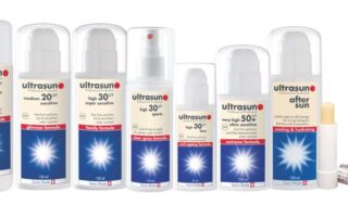 A row of nine Ultrasun suncream and skincare products, mostly in white bottles with blue labels. Each bottle shows the SPF number, formula type, and brand logo. On the far right is a small lip balm tube labelled “ultralip.”.