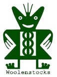A green, symmetrical cartoon figure with a wide smile, round eyes, radiating lines on its head, and stylised arms and legs. The body features abstract patterns. Below the figure, the word “Woolenstocks” appears in lowercase letters.