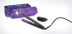 A black and purple hair straightener with a power lead is placed in front of a purple carrying case decorated with white swirls. The straightener's ceramic plates are visible, and a black clip accessory lies beside it on a white background.