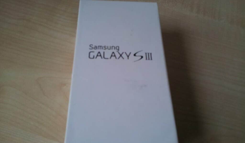 A rectangular white box with "Samsung GALAXY S III" printed in black text on the lid is placed on a light wooden surface. The box is closed and positioned slightly off-centre in the image.