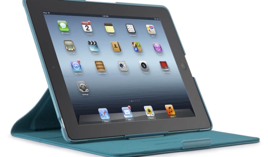 A black tablet in a blue protective case is propped up in a landscape orientation. The screen displays a grid of colourful app icons on a light blue background, resembling a typical home screen layout. The case forms a triangular stand to support the tablet upright.