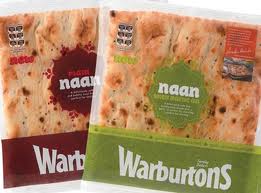 Two packs of Warburtons naan bread are shown side by side. One pack has a red label and is labelled "plain," while the other has a green label and is labelled "garlic & coriander." Both packs display the naan’s bubbled, golden surface.