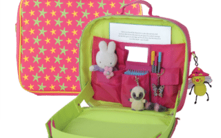 Open pink and green travel desk for children with star pattern. Inside are pockets holding a Miffy toy, a small plush mouse, pens, a butterfly clip, a notepad, and a comb. A smiley bee keyring hangs from the outside handle.