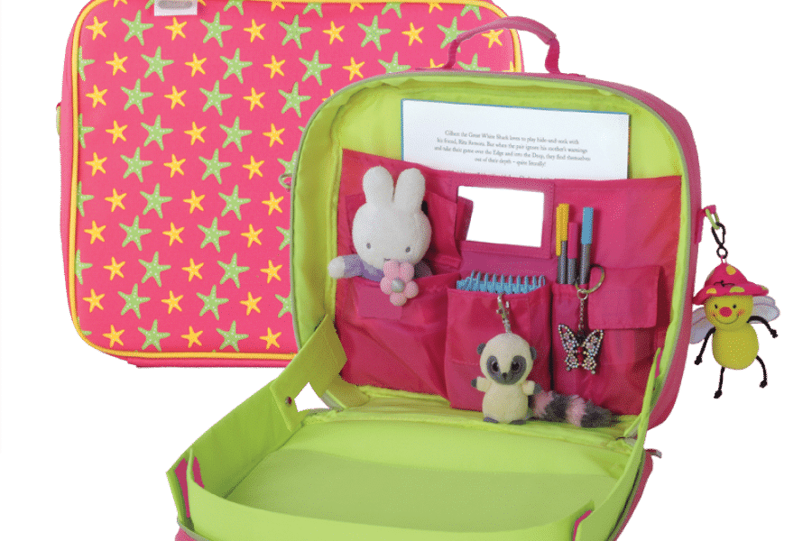Open pink and green travel desk for children with star pattern. Inside are pockets holding a Miffy toy, a small plush mouse, pens, a butterfly clip, a notepad, and a comb. A smiley bee keyring hangs from the outside handle.