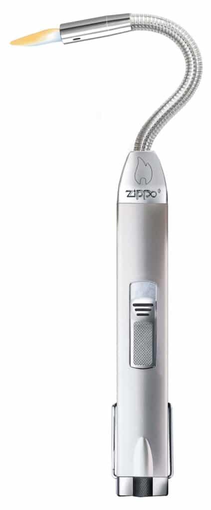 A silver Zippo lighter with a flexible, curved metal neck and a small blue and orange flame at the tip. The lighter has a thumb switch and the Zippo logo engraved on its body. The design is sleek and metallic, intended for precision lighting.