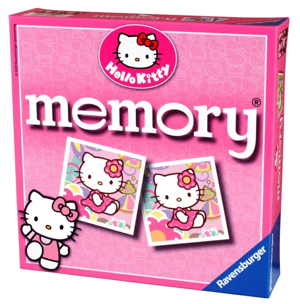 A pink Ravensburger "Hello Kitty Memory" game box features two matching cards with Hello Kitty holding a pink heart. The Hello Kitty logo is at the top, and a small Hello Kitty character is pictured wearing a pink scarf in the lower left corner.
