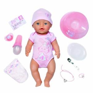 A baby doll wearing a pink hat and babygrow with a bunny design is surrounded by accessories: a dummy, bottle, feeding bowl, spoon, plate, nappy, birth certificate, bracelet, and necklace, all in shades of pink and white.