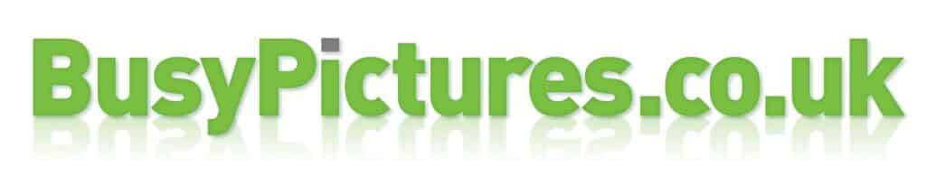 Green 3D text reads "BusyPictures.co.uk" with a slight shadow and mirrored reflection beneath the letters. The "P" in "Pictures" has a small grey square above it. The background is white, creating a clean and simple look.