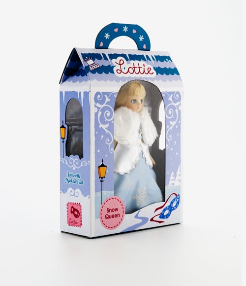 A boxed "Lottie" doll titled "Snow Queen" is shown. The doll wears a blue dress with a white fur cape. The packaging is winter-themed with snowflakes, lamp posts, and icy decorations, and features a blue handle on top.