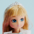 A doll with long blonde hair, blue eyes, and a white crown tiara on its head, wearing a light blue and white outfit, is set against a plain light blue background.