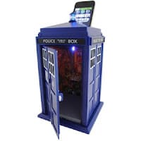 A blue rectangular TARDIS-shaped box with white windows, labelled “POLICE PUBLIC CALL BOX,” stands with its door open. A small blue light is on top, and a phone sits in a slot above the roof. The interior glows with orange and blue lights.