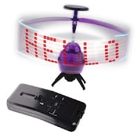 A small purple flying toy helicopter with spinning blades displays the word “HELLO” in red LED lights. Below it is a black remote control with several buttons and a slider for operating the toy.