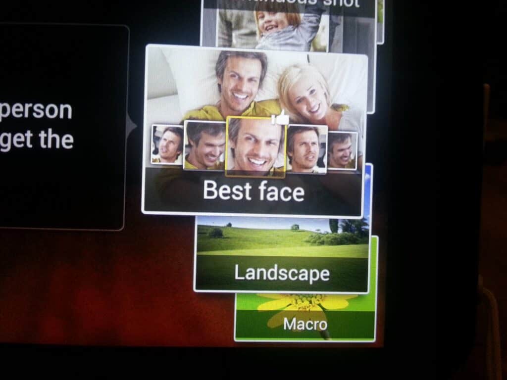 A camera screen displays different photo mode options. "Best face" is selected, showing multiple thumbnails of a smiling man in different poses. Below it, other modes like "Landscape" with a green field and "Macro" with a yellow flower are visible.