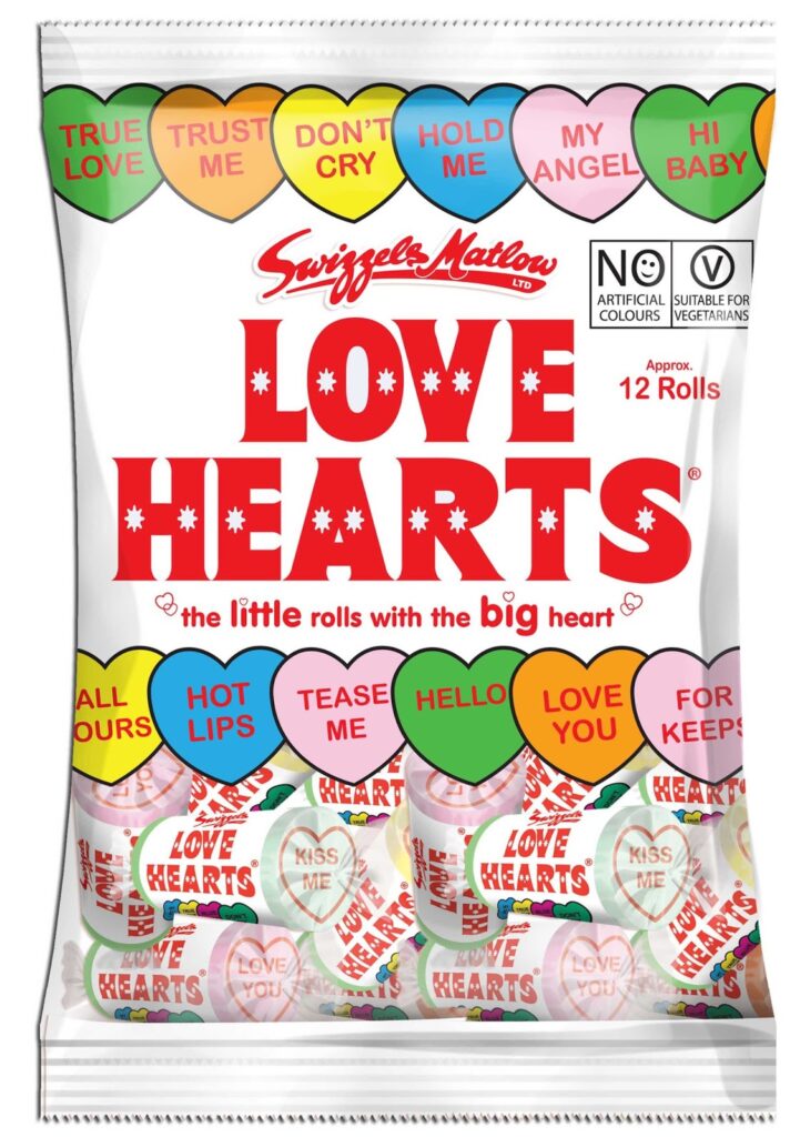A bag of Swizzels Matlow Love Hearts sweet rolls. The packaging is white with colourful sweet hearts on top, each displaying phrases like "TRUE LOVE," "MY ANGEL," and "HI BABY." The main text reads "LOVE HEARTS" in bold red letters.