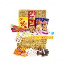 A woven basket filled with various colourful retro sweets, including Dip Dab, Fizz Wiz, candy sticks, fizzy cola bottles, foam bananas, love hearts, and other assorted confectionery, all arranged in a vibrant, eye-catching display.