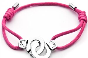 A pink cord bracelet features two interlocking silver circles as a centrepiece. The cords are knotted on both sides of the circles and have silver metal tips at the ends. The design is simple and modern, with an adjustable fit.
