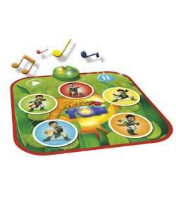 A colourful musical play mat featuring cartoon characters in circles, a central blue radio graphic, musical notes, and a large green button. The mat has a vibrant design with green, red, and yellow accents, and is shown with toy musical notes nearby.