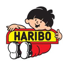 Cartoon boy with black hair, wearing a red outfit and white trainers, smiles whilst leaning over a yellow sign with red edging that says "HARIBO" in bold black letters. The background is plain white.