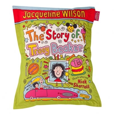 A colourful cushion designed as the book cover of "The Story of Tracy Beaker" by Jacqueline Wilson, illustrated by Nick Sharratt. The cover shows a cartoon girl, playful icons, and bright text in pink, orange, and yellow on a green background.