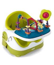 A green and white baby activity seat with a blue tray, featuring colourful toys including rings, a flower, and animal shapes attached to the tray for sensory play. The seat has a rounded backrest and sturdy base for support.