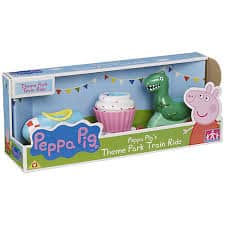 A boxed Peppa Pig toy set labelled "Theme Park Train Ride" featuring a blue train carriage, a pink cupcake carriage, and a green dinosaur carriage. The packaging displays colourful bunting and Peppa Pig's image on the right.