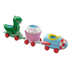 Three colourful toy train carriages: the first shaped like a green dinosaur, the second like a pink cupcake with white icing, and the third as a blue racing car with a red-chequered front. All carriages are linked and have red wheels.