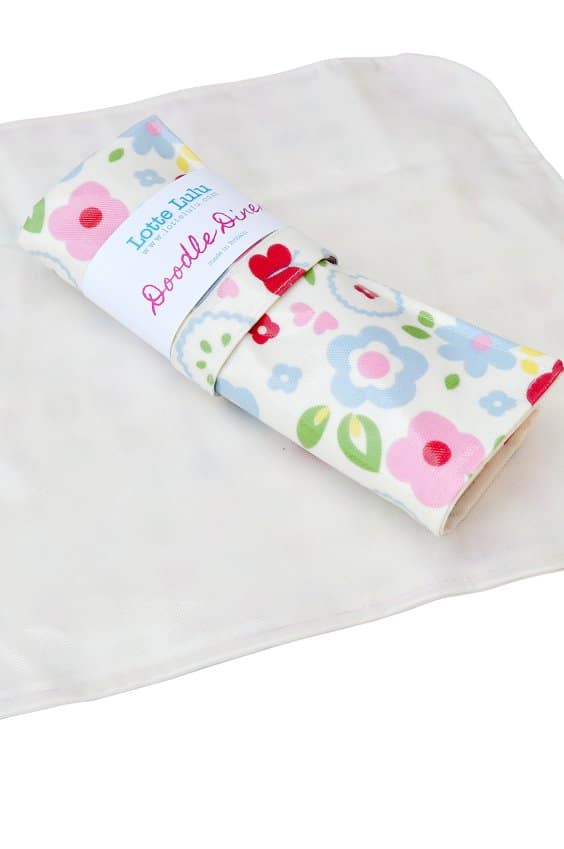 A white, square cloth lies flat beneath a rolled-up, rectangular item wrapped in a floral-patterned fabric. The wrapper reads “Love, Lulu Doodle Dive.” The background is white, giving a clean, minimal appearance.