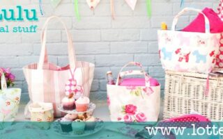 A pastel-themed display featuring floral and striped tote bags, a picnic hamper with fabric liners, teacups, flowers, cupcakes, and bunting against a light brick wall. Text reads “Lotte Lulu, Pretty practical stuff” and “www.lottelulu.com”.